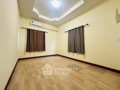 Spacious empty room with wooden flooring and ceiling light, ideal for customization.
