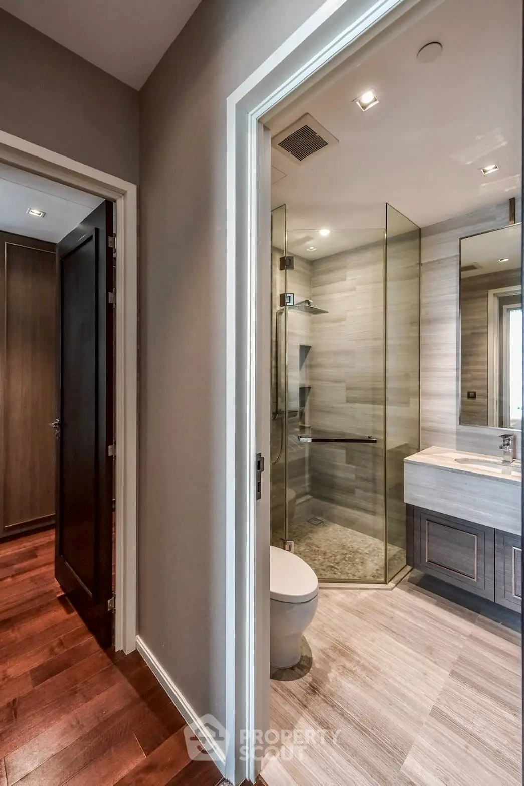 Modern bathroom with glass shower and sleek vanity in contemporary apartment.