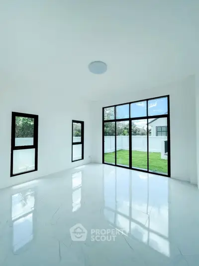 Bright and spacious room with large windows overlooking a lush green garden, perfect for modern living.