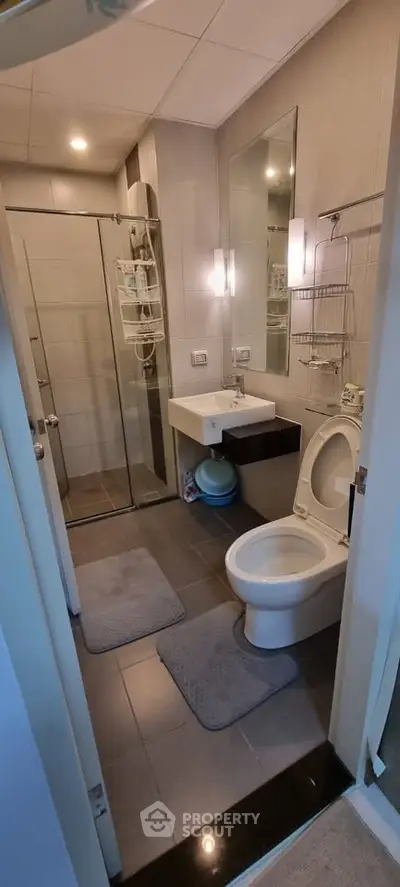 Modern bathroom with glass shower, sleek fixtures, and elegant lighting.