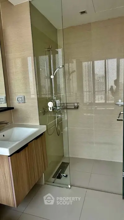 Modern bathroom with glass shower and sleek sink in contemporary apartment.