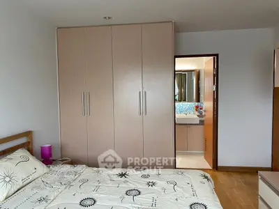 Cozy bedroom with floral bedding and ensuite bathroom in modern apartment