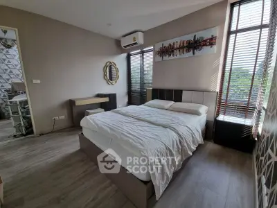 Modern bedroom with stylish decor and large windows offering natural light and scenic views.