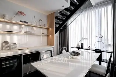 Modern kitchen with sleek design, open layout, and elegant dining area under a staircase.