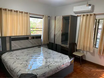 Spacious bedroom with modern furniture and large windows offering natural light.