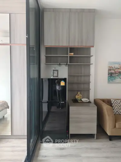 Modern interior with sleek black fridge and stylish shelving in cozy living area.