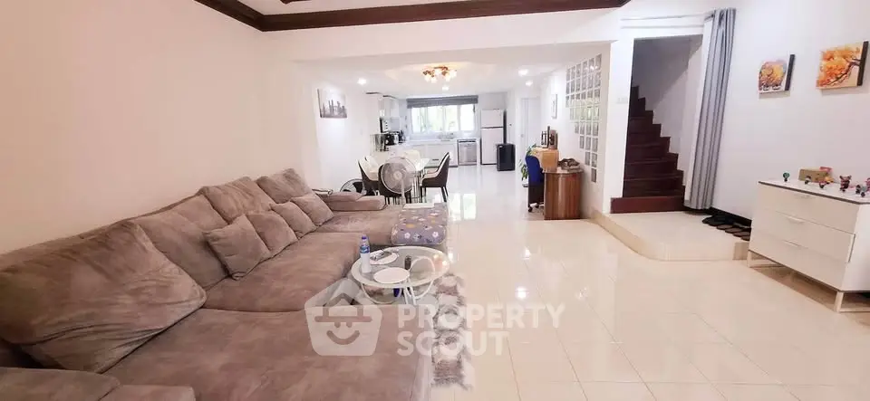 Spacious open-plan living room with plush sofa and modern kitchen in a stylish home.