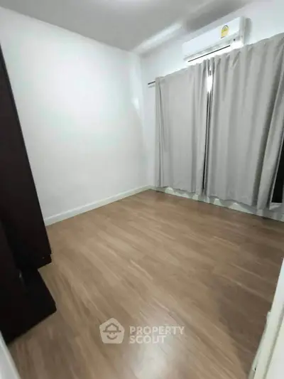 Spacious empty room with wooden flooring and air conditioning, ideal for customization.