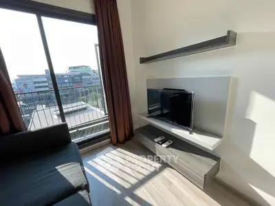 Modern living room with sleek TV setup and large window offering city view