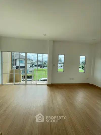 Spacious empty room with large windows and wooden flooring, perfect for customization.