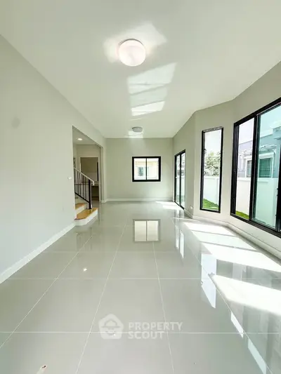 Spacious modern living room with large windows and glossy tiled floors, perfect for natural light lovers.