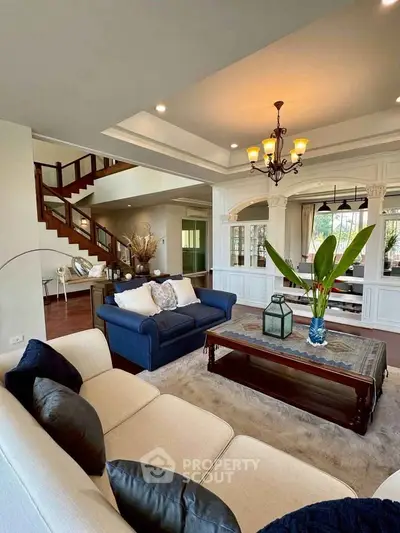 Luxurious living room with elegant decor and spacious layout, featuring a grand staircase and stylish furniture.