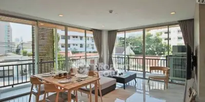 Spacious corner unit living room with panoramic windows and modern decor in urban setting.