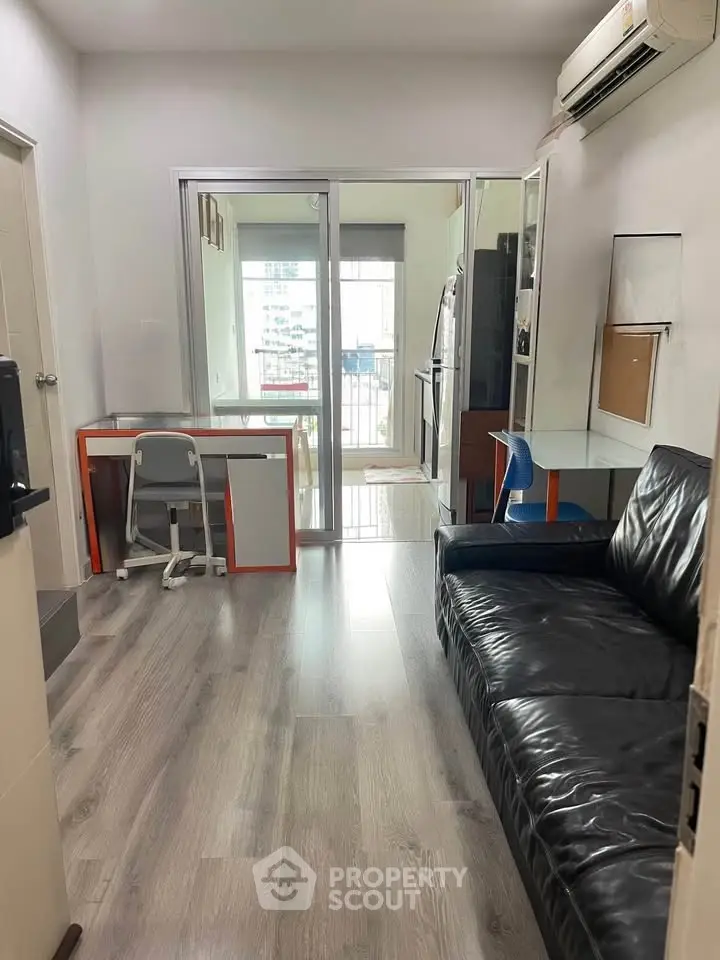 Modern living room with sleek black sofa and study area, featuring stylish flooring and air conditioning.