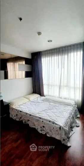 Cozy bedroom with large window and modern decor in a stylish apartment.