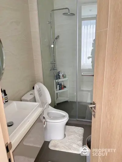 Modern bathroom with a sleek glass shower enclosure, well-maintained toilet, and a spacious sink area, perfect for a refreshing start to the day.