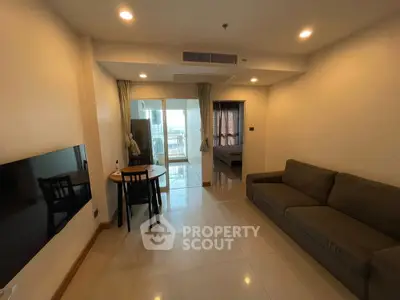 Modern living room with cozy sofa and dining area, leading to a balcony with city view.