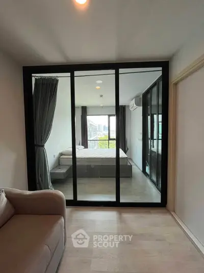 Modern apartment with glass-walled bedroom and cozy living area, offering a bright and airy ambiance.