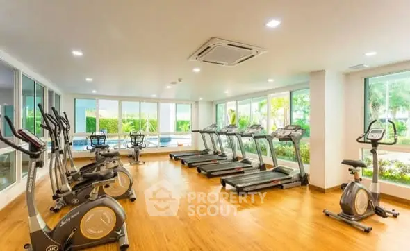 Spacious gym with modern equipment and large windows offering garden views.