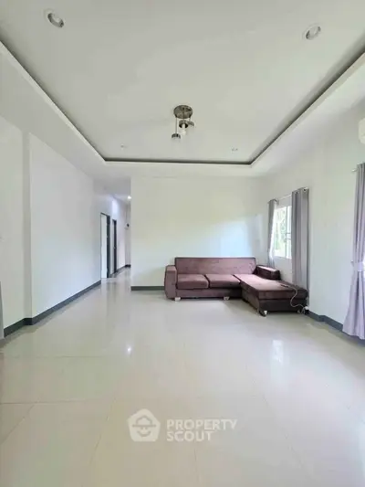 Spacious living room with modern sofa and natural light, perfect for relaxation and entertaining.