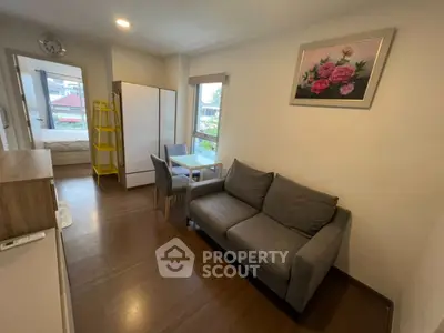 Cozy living room with modern decor and natural light, featuring a comfortable sofa and dining area.