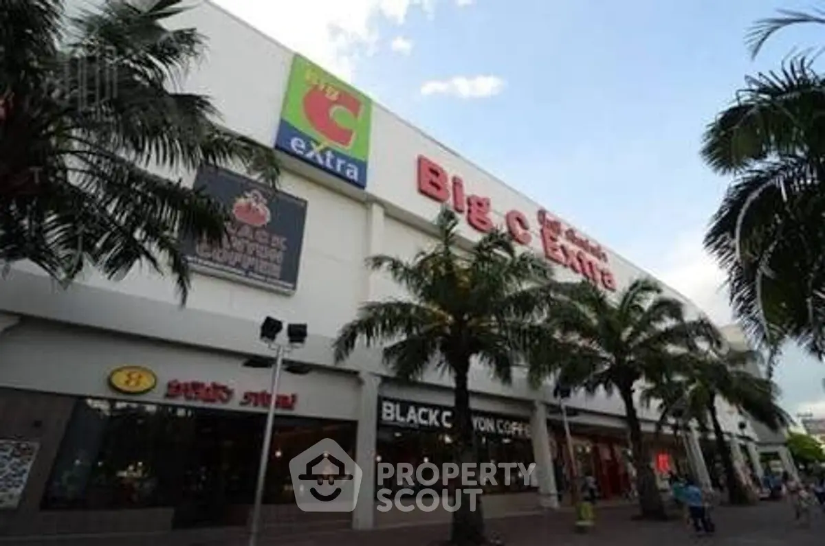 Modern commercial building exterior with palm trees and retail signage