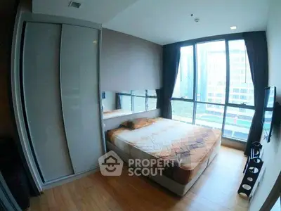 Modern bedroom with large windows and city view in a high-rise apartment.