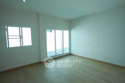 Spacious empty room with large windows and wooden flooring, ideal for customization.