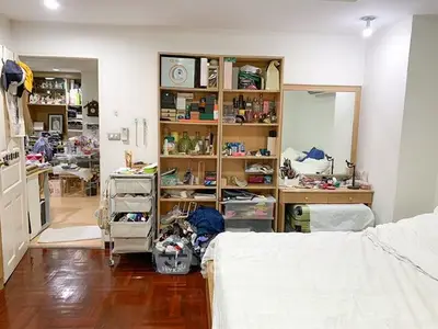 Cozy bedroom with wooden flooring and organized shelves in a modern apartment.