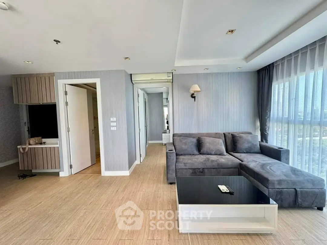 Spacious modern living room with large windows and stylish gray sectional sofa.