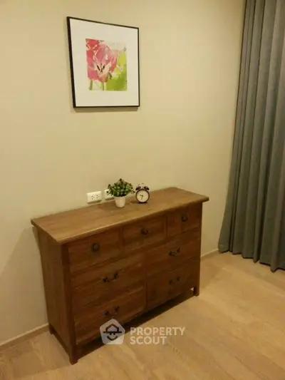 Cozy bedroom corner with wooden dresser and floral artwork, perfect for a serene ambiance.