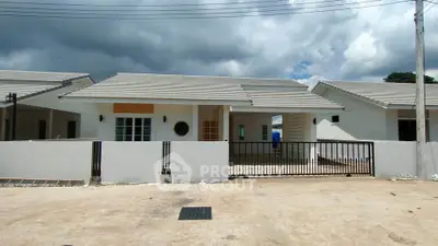 Charming single-story home with modern design and spacious driveway under cloudy sky.