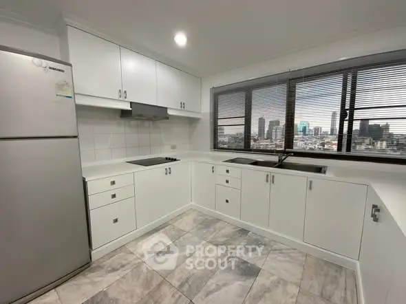 Modern kitchen with city view, featuring sleek white cabinets and stainless steel appliances.