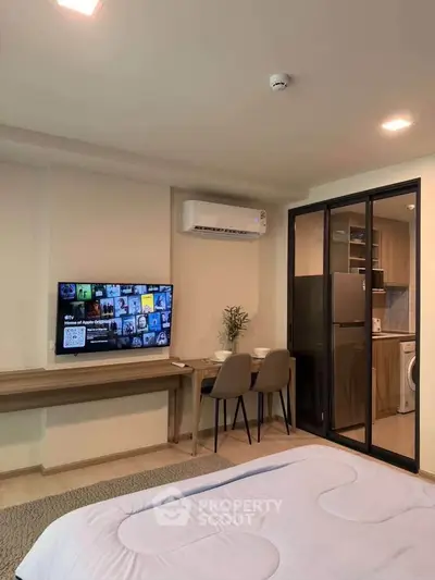 Modern studio apartment with cozy bedroom and compact kitchen featuring a washing machine and dining area.