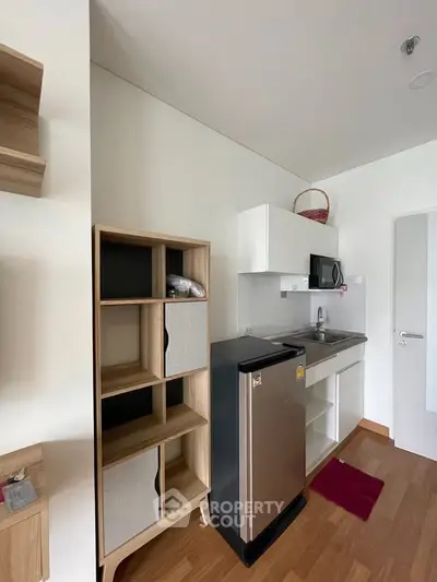 Modern compact kitchen with sleek appliances and stylish storage solutions in a cozy apartment setting.