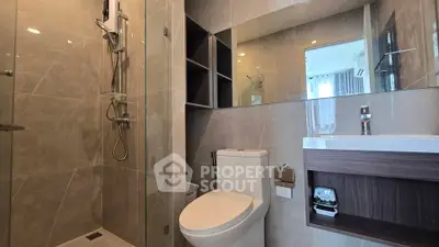 Modern bathroom with glass shower and sleek fixtures in contemporary apartment.