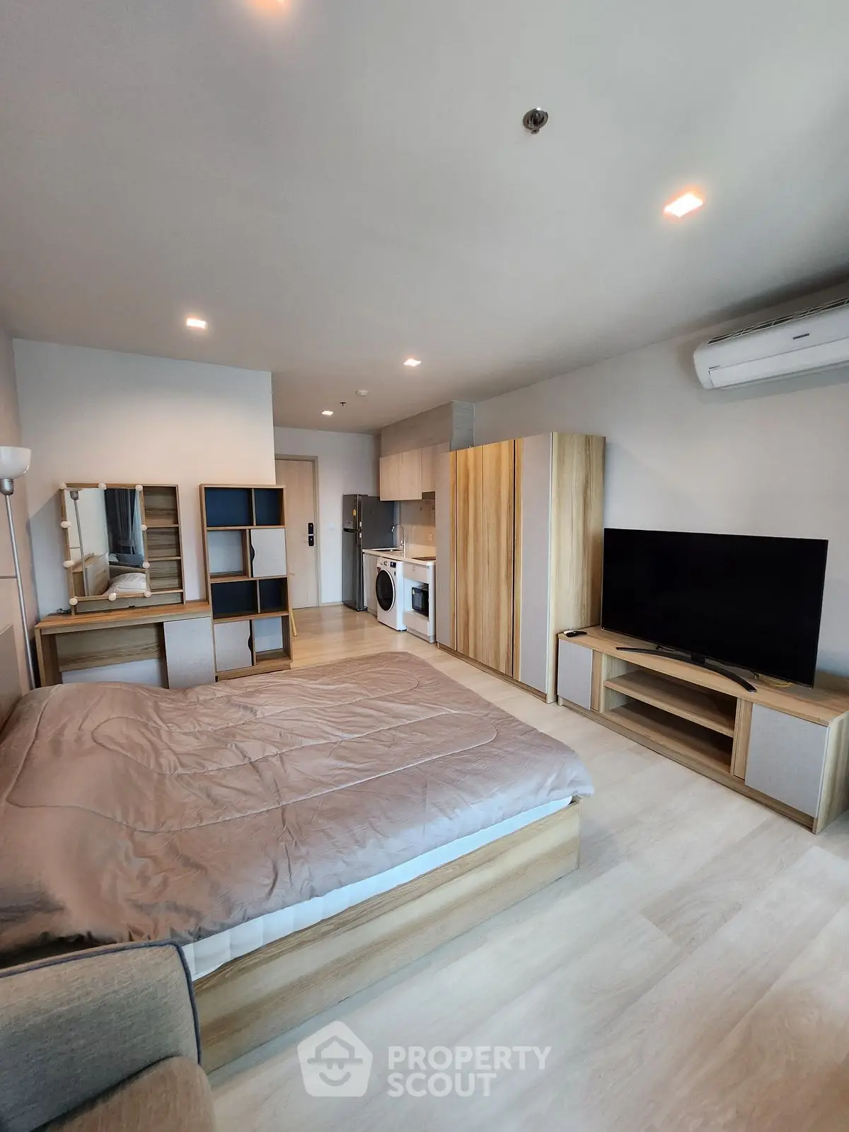 Modern studio apartment with open layout, featuring a cozy bed, sleek kitchen, and stylish furniture.