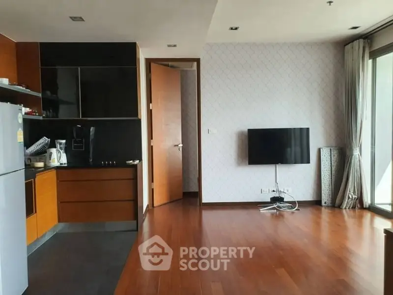 Spacious modern living room with wooden floors and sleek kitchen area.