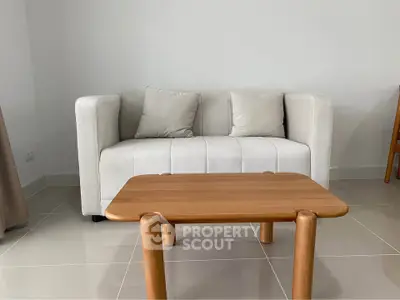 Modern living room with sleek white sofa and wooden coffee table on polished tile floor.