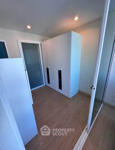 Spacious storage room with modern white cabinets and wooden flooring