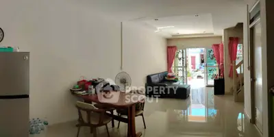 Spacious living room with modern decor and natural light, featuring a cozy seating area and dining table.