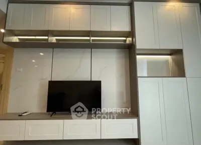 Modern living room with sleek built-in cabinetry and flat-screen TV, showcasing elegant design and ample storage.