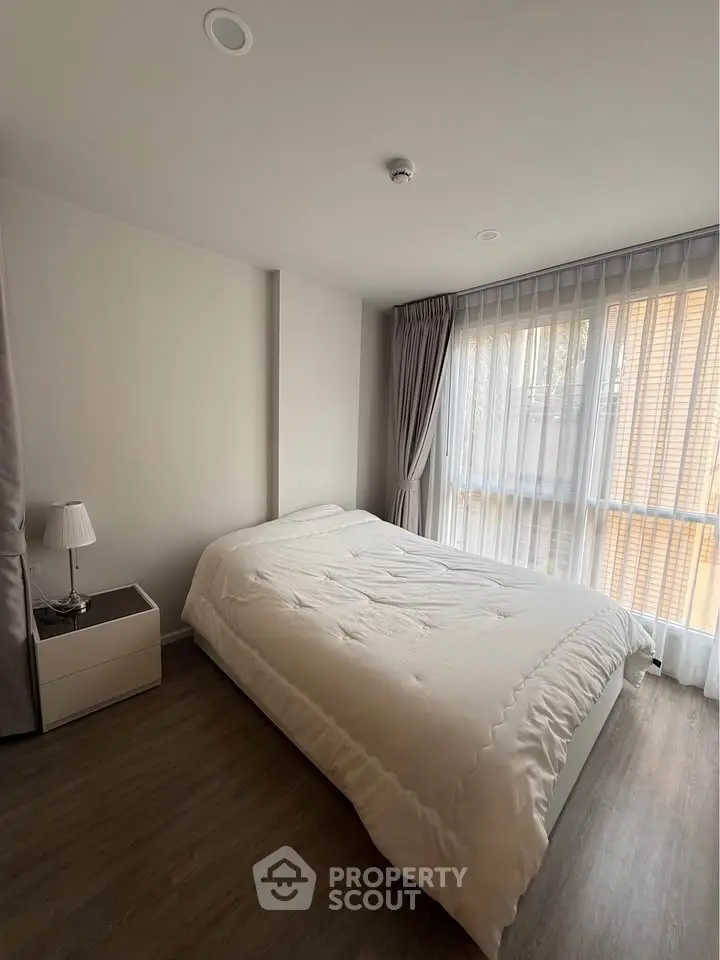 Cozy bedroom with natural light and modern decor, featuring a comfortable bed and elegant curtains.