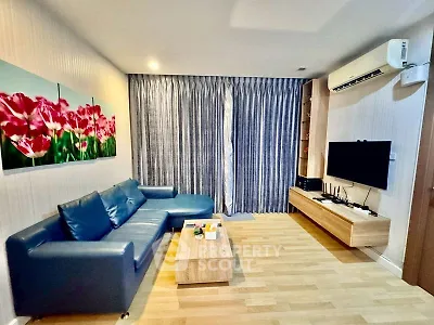 Modern living room with blue sofa, wall-mounted TV, and vibrant floral artwork.