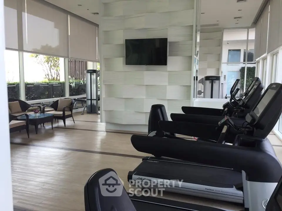 Modern gym with treadmills and lounge area in luxury apartment building