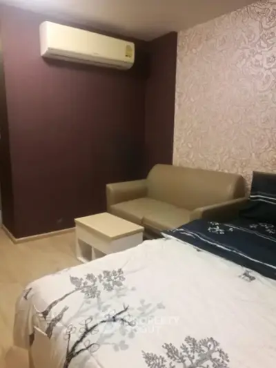 Cozy bedroom with air conditioning and stylish wallpaper, featuring a comfortable sofa and modern decor.