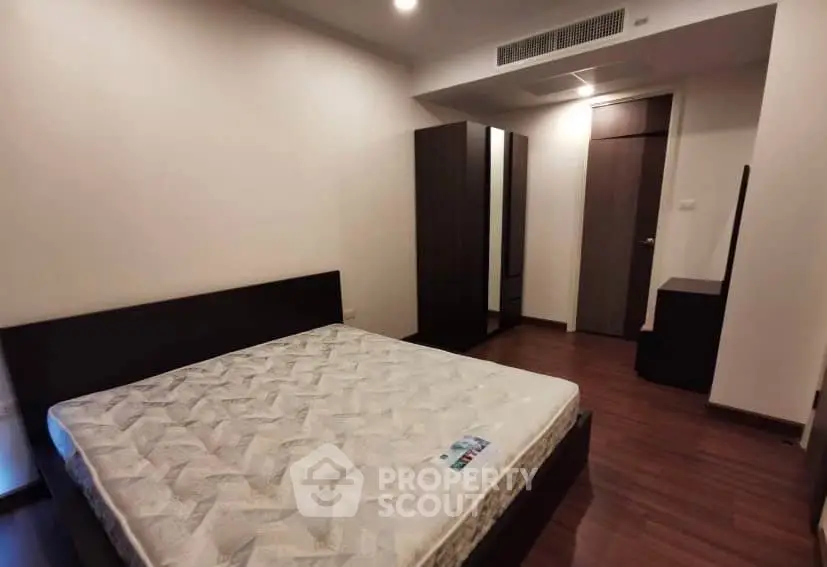 Spacious bedroom with modern furniture and wooden flooring in a stylish apartment.