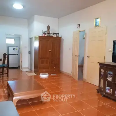 Spacious living room with wooden furniture and tiled flooring, featuring a cozy ambiance.