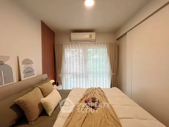 Cozy bedroom with modern decor and natural light from large window.