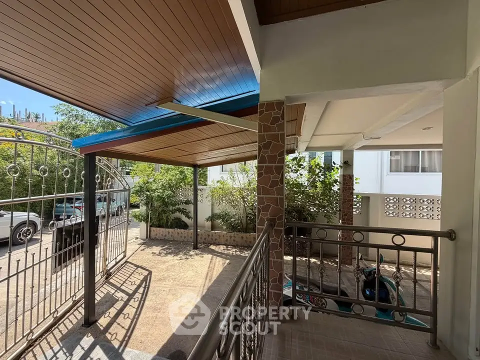 Charming residential entrance with covered parking and lush greenery